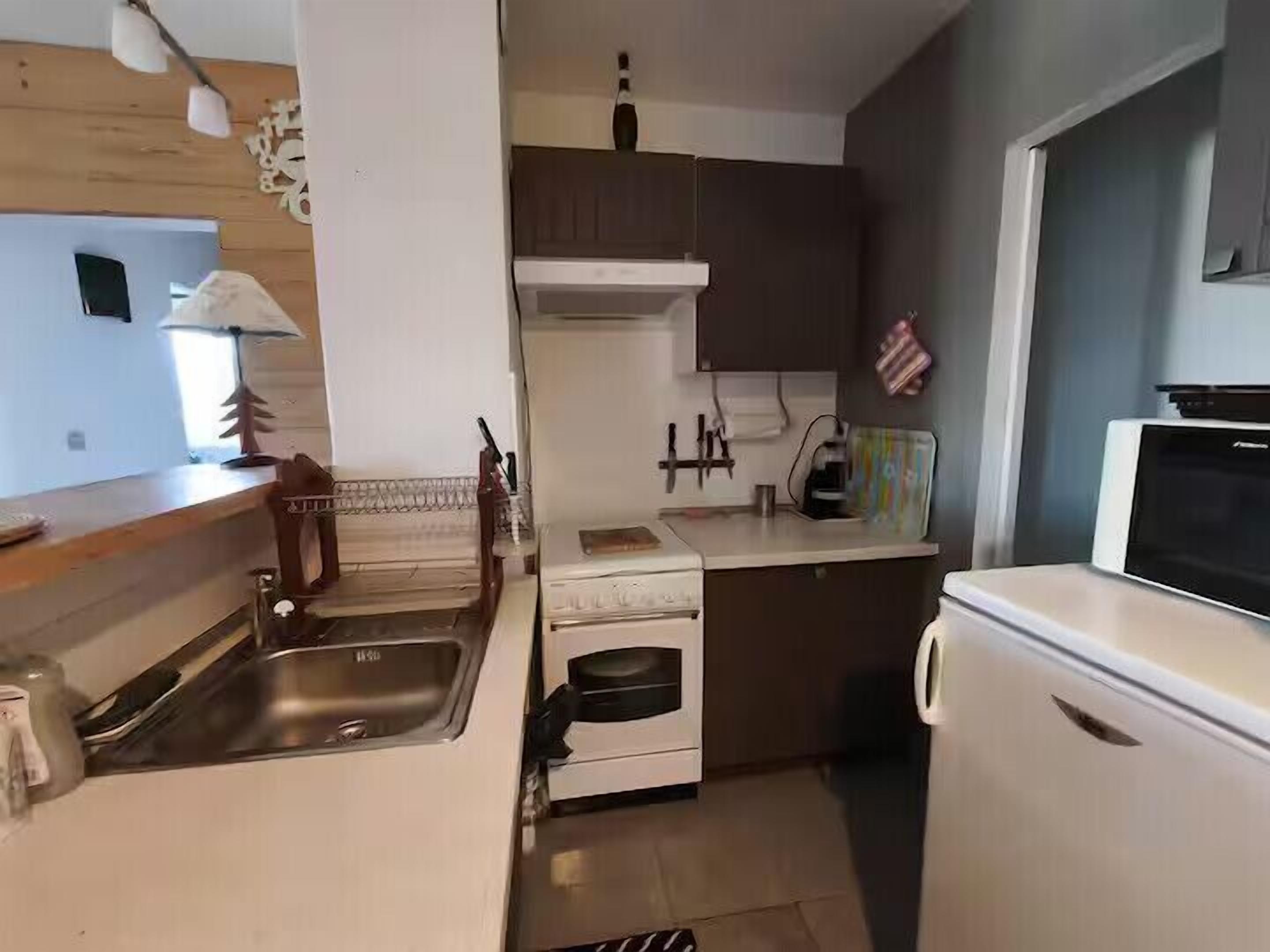 A compact kitchen with a sink, stove, and microwave.