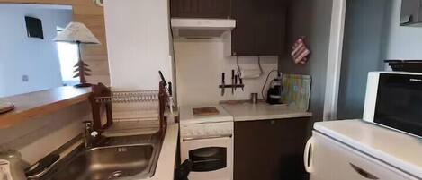 A compact kitchen with a sink, stove, and microwave.