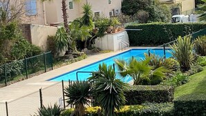 Ein Wohngebiet mit einem Schwimmbecken, umgeben von üppiger Vegetation und Palmen.