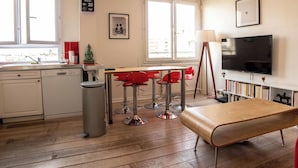 A modern kitchen with a dining area, a large window, and a television. - Spacious apartment near Père Lachaise (Paris)