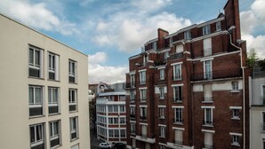 A multi-story residential building with a mix of brick and plaster facades, featuring balconies and a central courtyard. - Spacious apartment near Père Lachaise (Paris)