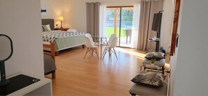 Ein Hotelzimmer mit Bett, Tisch mit Stühlen, Fernseher und Blick ins Freie.