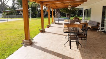 An outdoor patio with a pool table, seating area, and a covered section with wooden beams.