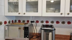 Cozinha com armários brancos, micro-ondas e cafeteira.