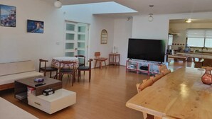 Uma sala de estar ampla com uma mesa de jantar de madeira, uma televisão de tela plana e uma janela grande.