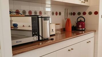 A kitchen with white cabinets, a microwave, a toaster, and a kettle on the counter.