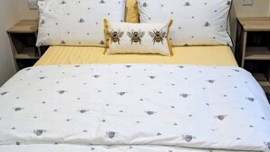 Een opgemaakt bed met een witte deken en gekleurde kussens, een houten hoofdbord en bijpassende nachtkastjes.