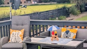 Een terras met rieten meubilair, een schotelantenne en een kleine tafel met een blauw-witte parasol.