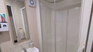 Een badkamer met een wit wastafel, spiegel en een douchecabine van glas.