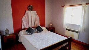 A bedroom with a bed, a nightstand, a lamp, a window with curtains, and a wall-mounted decoration. - Holiday Home 'Les Cousines' with Mountain View, Private Terrace and Wi-Fi (Lavoûte-Chilhac)