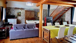 A cozy living area with a sofa, dining table, and a staircase. - Holiday Home 'Les Cousines' with Mountain View, Private Terrace and Wi-Fi (Lavoûte-Chilhac)