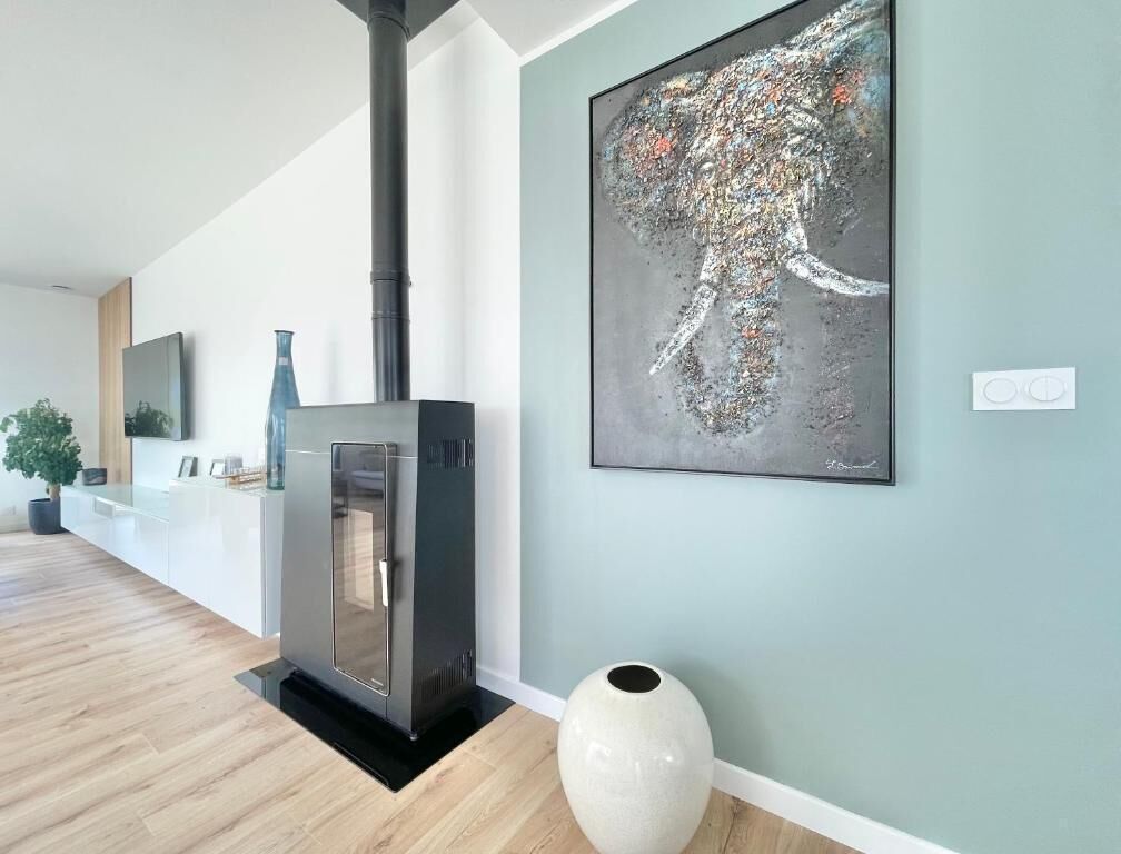 A modern kitchen with a built-in stove, a large vase, and a contemporary painting on the wall.