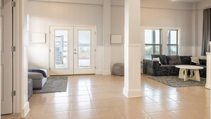 A spacious living area with a large window, a sofa, a coffee table, and a ceiling fan.
