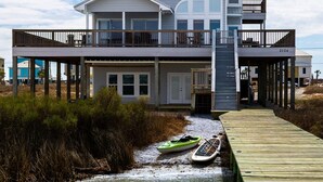 A two-story house with a balcony, a dock, and a boat.