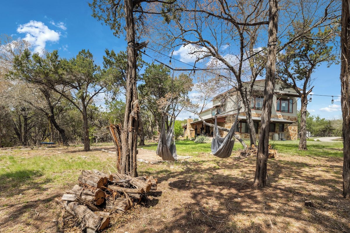 Une maison aux murs en pierre, entourée d’arbres et sous un ciel dégagé.