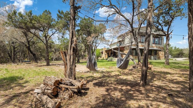 A house with a stone exterior, surrounded by trees and a clear sky.