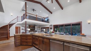 A spacious kitchen with a large island, upper-level balcony, and a view of the outdoors.