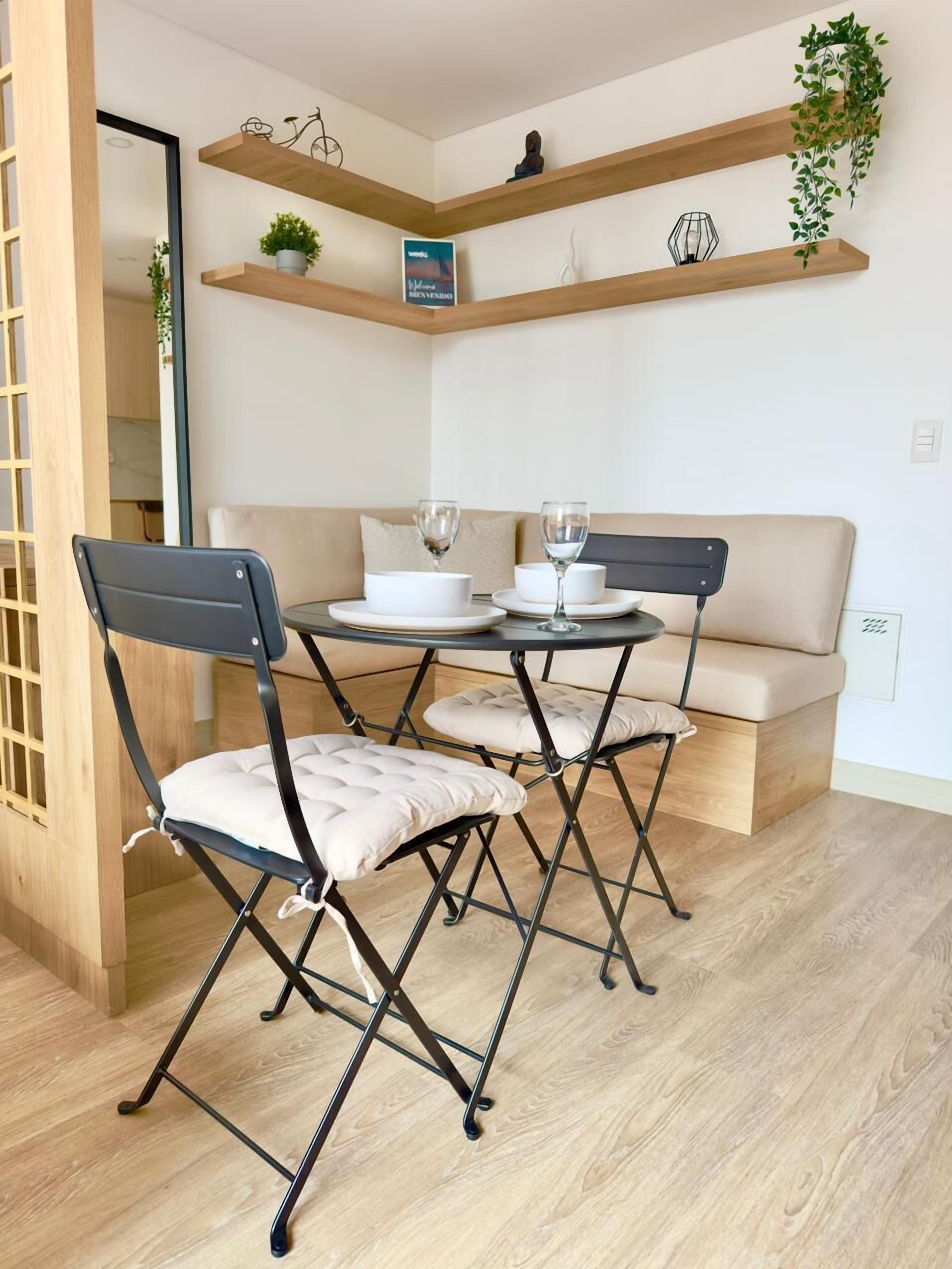 A compact dining area with a round table, two chairs, and a sofa.