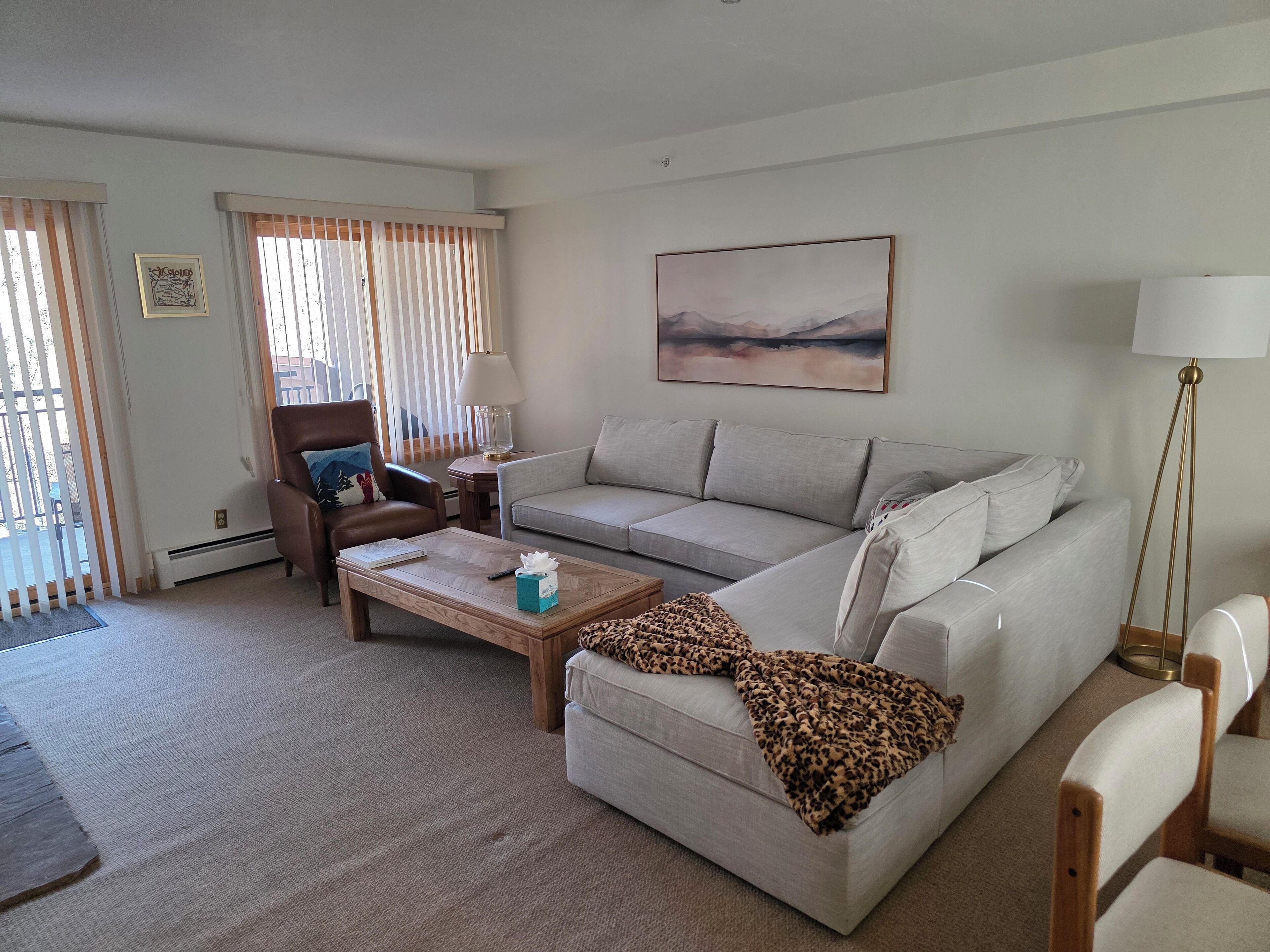 A living room with a sofa, armchairs, a coffee table, and a lamp.