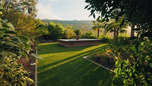 A well-maintained garden with a central circular structure, surrounded by lush greenery and a clear view of distant hills. - Maison du monde (Costa Adeje)