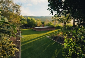 A well-maintained garden with a central circular structure, surrounded by lush greenery and a clear view of distant hills. - Maison du monde (Costa Adeje)