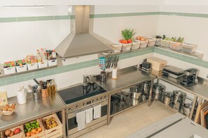 A modern kitchen with stainless steel appliances, organized storage for fruits and vegetables, and a variety of cooking utensils. - Maison du monde (Costa Adeje)