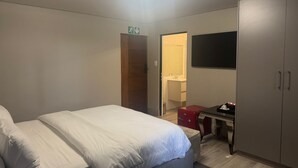Une chambre d’hôtel équipée d’un lit, d’un bureau, d’une armoire et d’un téléviseur.
