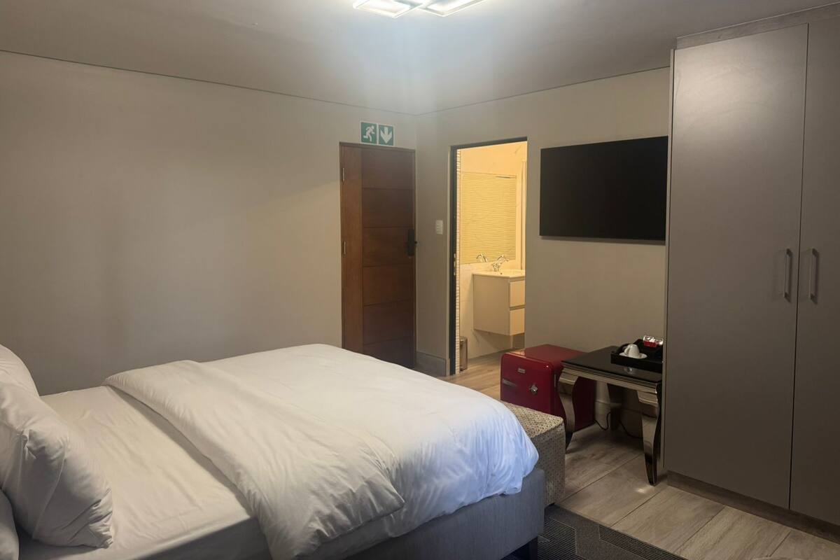 Een hotelkamer met een bed, bureau, kledingkast en televisie.
