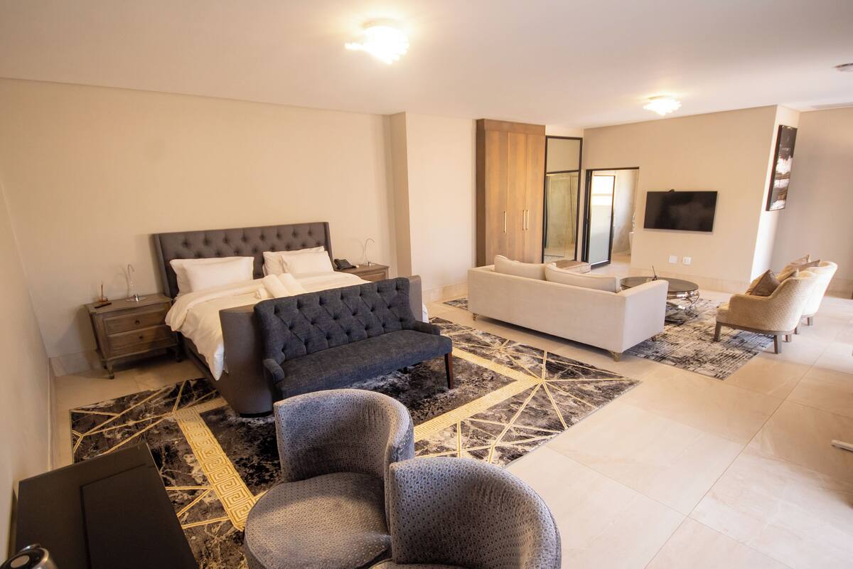 Een moderne slaapkamer met een groot bed, een bank en een televisie.
