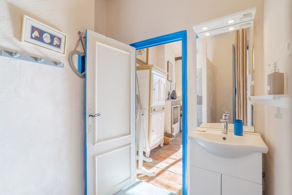 An open door leading to a bathroom with a white sink, mirror, and a blue-framed mirror. - Chambre Bleu Guest Room with Shared Garden and Wi-Fi (Lagorce)