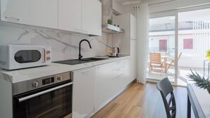 A modern kitchen with white cabinets, a built-in microwave, a stove, and a sink. - Albamare (Alba Adriatica)