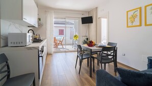 A modern kitchen with white cabinets, a microwave, and a dining area with a table and chairs. - Albamare (Alba Adriatica)