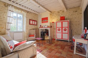 A room with a bed, a small table, a chair, a radiator, a window, and a door with a red flower design. - “Chambre Coquelicot” Guest Room with Shared Garden and Wi-Fi (Lagorce)