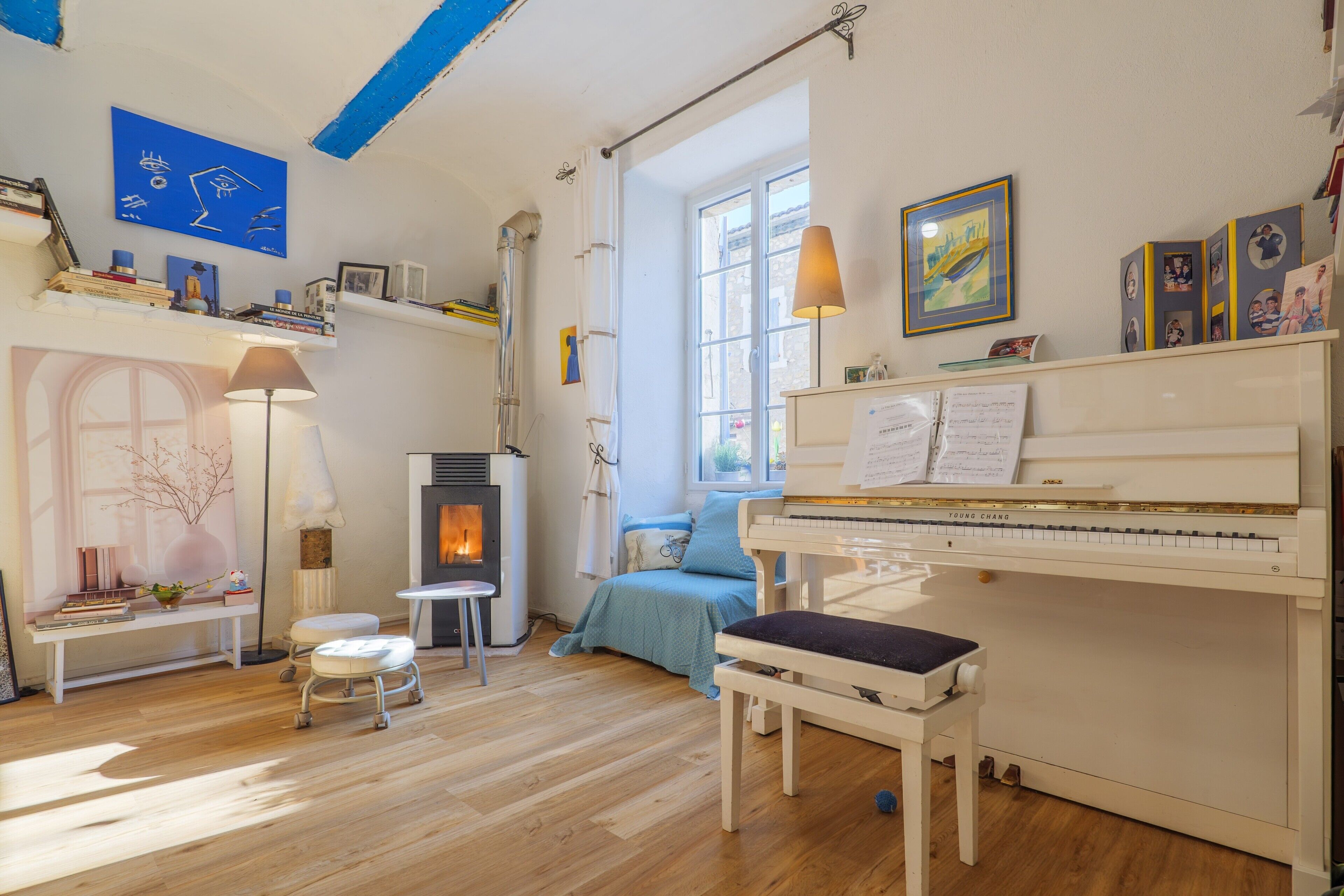Ein Zimmer mit Klavier, Kamin, Bank und Blick aus dem Fenster.