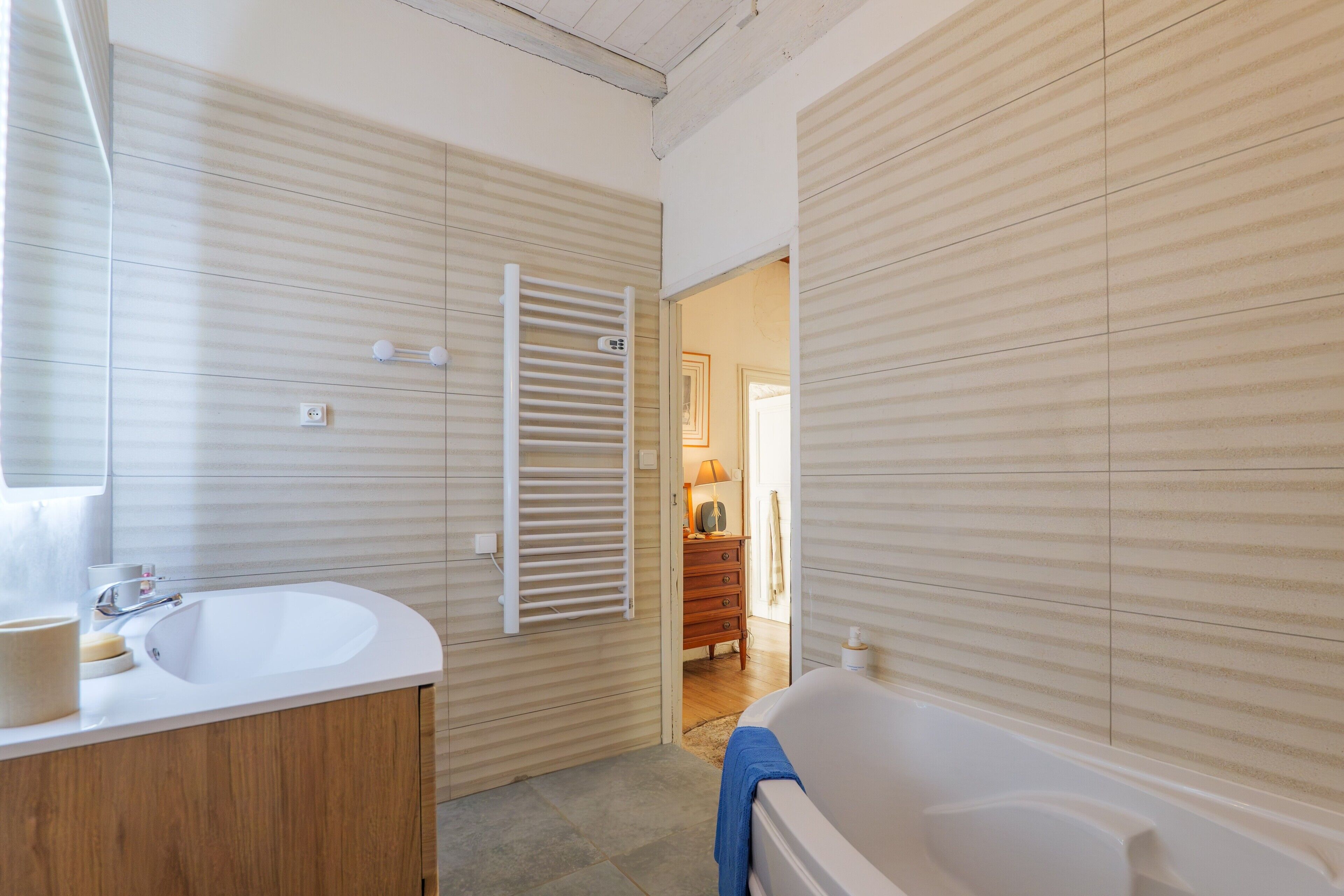 Une salle de bain avec un lavabo blanc, un meuble-lavabo en bois et une baignoire.