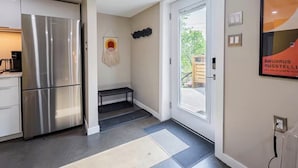 Een moderne keuken met een roestvrijstalen koelkast, een bankje en een deur naar buiten.