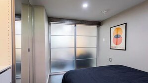 Een slaapkamer met een bed, een schuifdeurkast en een ingelijst kunstwerk aan de muur.