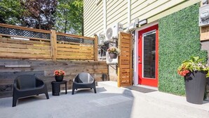 Een terras met twee stoelen, een kleintje tafeltje en een bloempot.