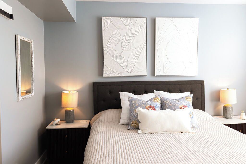 A neatly arranged bedroom with a large bed, two bedside tables, and two wall-mounted lamps.
