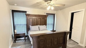 Ein Schlafzimmer mit einem hölzernen Bett, einem Deckenventilator und einem Fenster mit Jalousien.