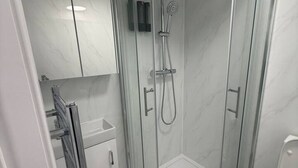 Un bany modern amb dutxa envidriada, vàter i rentapel.