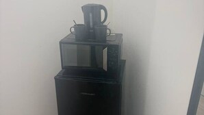 Nevera negra compacta amb un forn de microones i una cafetera a la part superior.