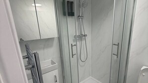 Un bany modern amb dutxa envidriada, vàter i rentapans.