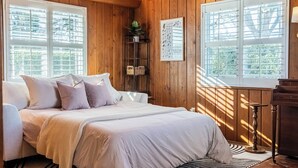 A bedroom with a bed, a bedside table, a lamp, a window with blinds, a plant on a shelf, and a framed chart on the wall. - Fairmount Manor off of Lake Hollingsworth. Games, Gym, and Gather! Sleeps 8 (Lakeland)