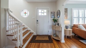 A staircase leading to a door with a welcome mat, a small table with a lamp, and a couch in a well-lit room with wooden floors. - Fairmount Manor off of Lake Hollingsworth. Games, Gym, and Gather! Sleeps 8 (Lakeland)