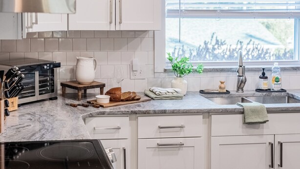 A modern kitchen with white cabinets, a built-in oven, a sink, and a window with blinds. - Fairmount Manor off of Lake Hollingsworth. Games, Gym, and Gather! Sleeps 8 (Lakeland)