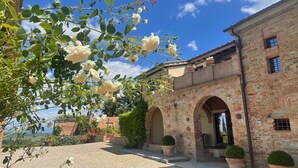 A stone building with arched doorways, a courtyard, and potted plants. - Villa le Murate by MMega (Montaione)