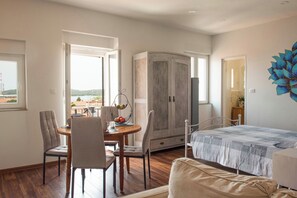 A room with a bed, a dining table with chairs, a wardrobe, and a view of the outdoors. - Focus Apartment - sea view near Arena in Pula (Pula)