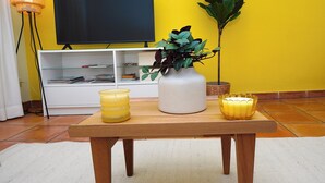 Una sala de estar con televisor, una mesa de madera y una planta en maceta.
