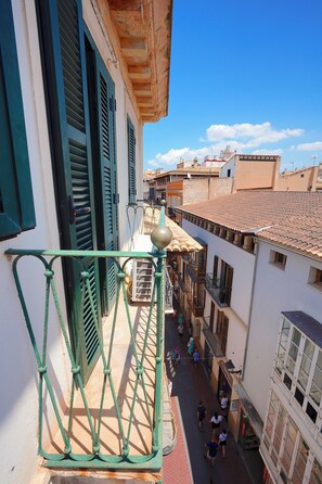 A narrow street with buildings on either side, balconies with metal railings, and a clear blue sky. - Can Carrio Turismo de interior (Palma de Mallorca)